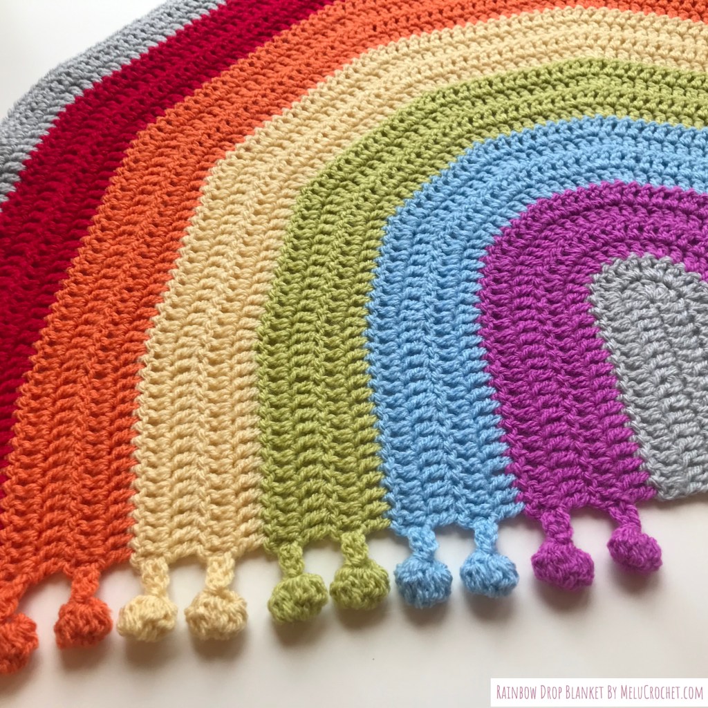 Zoomed in rainbow colours blanket with integrated bobble pom pom fringe