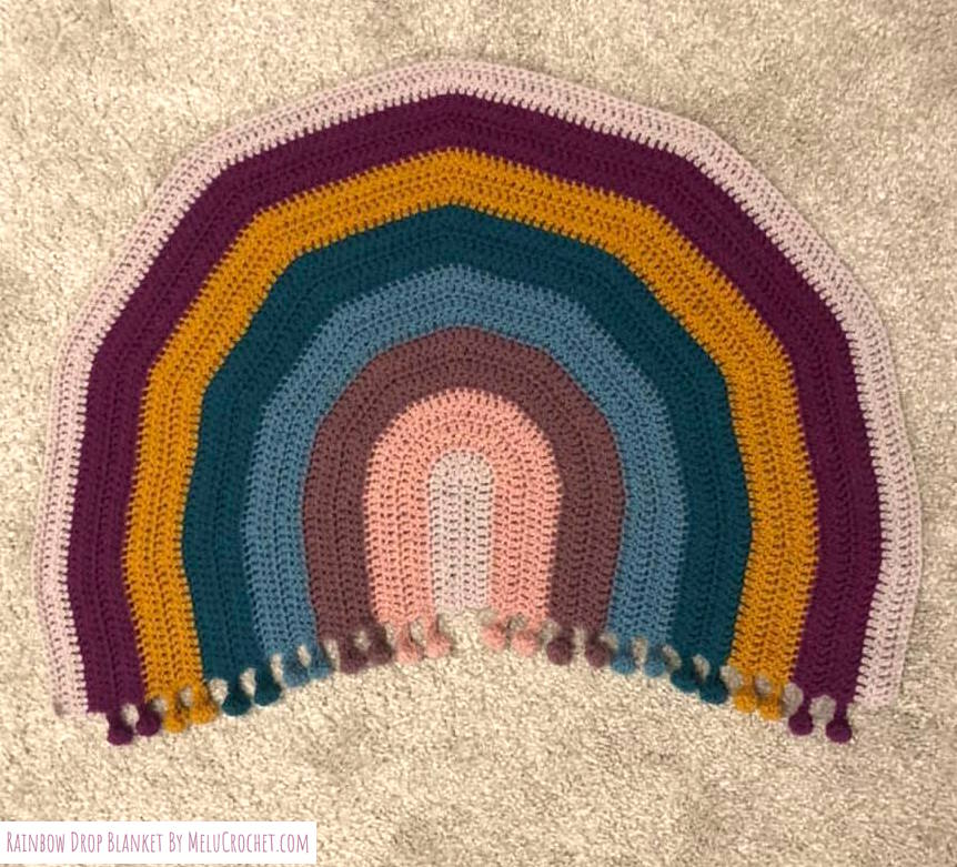 Rainbow shaped blanket with bobble pom pom fringe, muted colours